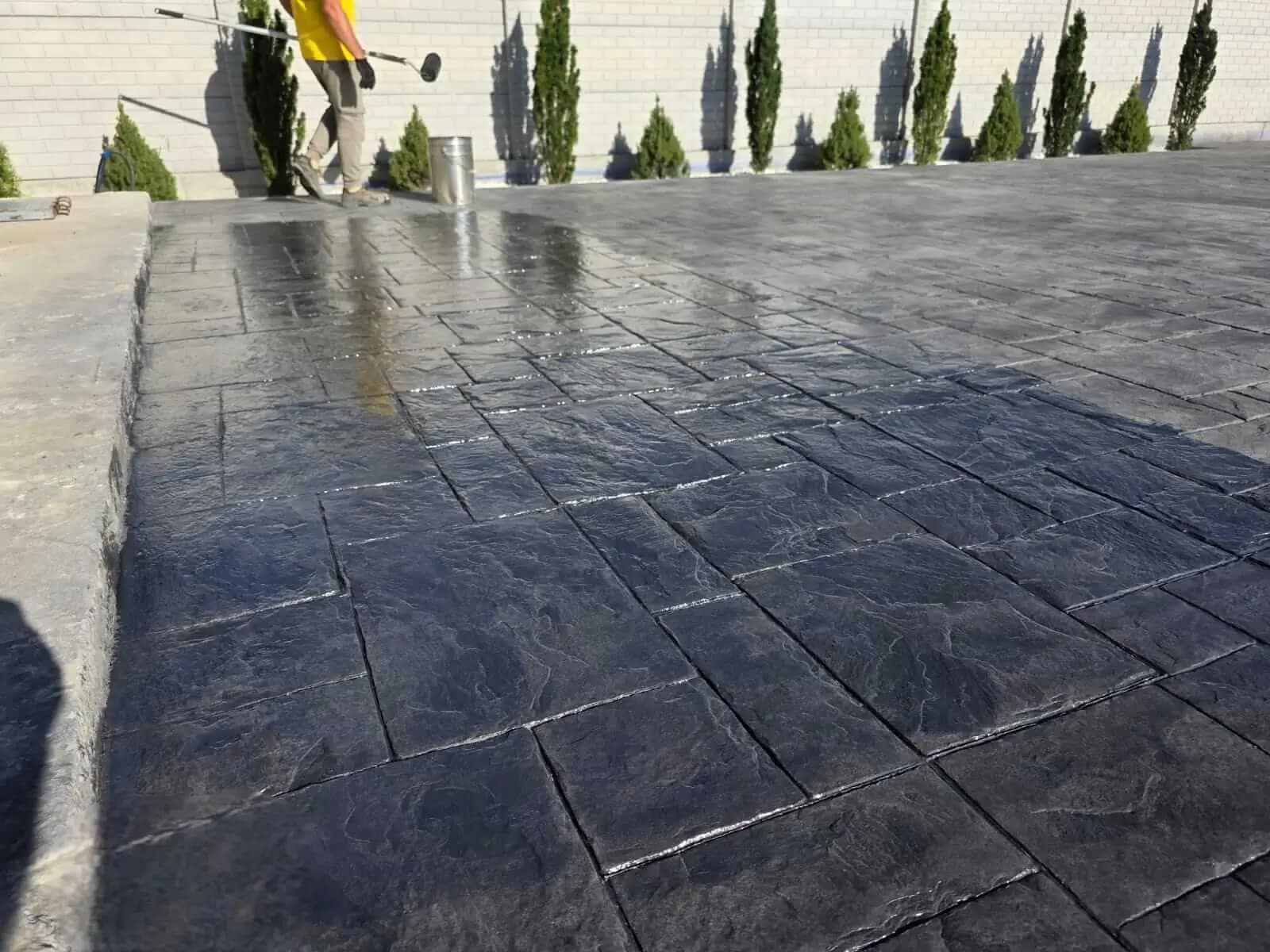 Curte mare cu beton amprentat negru grafit în proces de sigilare realizată de RBETON