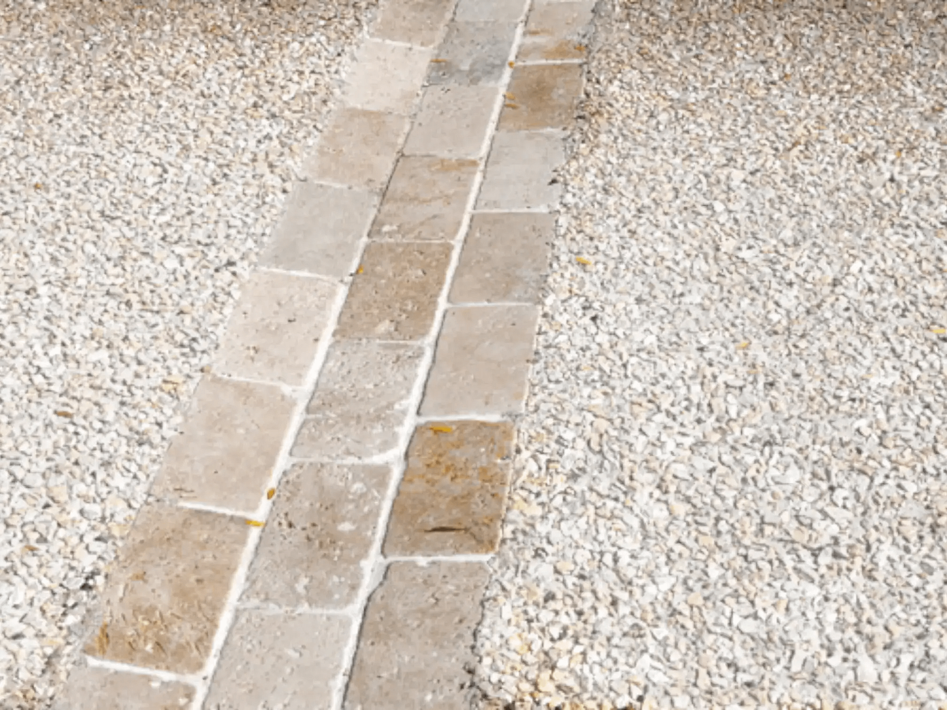Detaliu de pavaj exterior care combină o alee din dale de piatră cu zone laterale din beton dezactivat (piatră spălată).